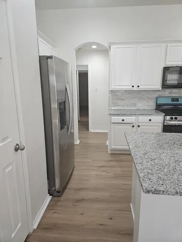 a kitchen with granite countertop a refrigerator and microwave