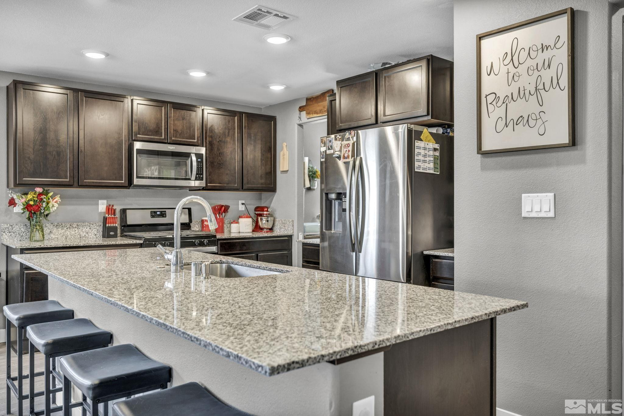a kitchen with kitchen island granite countertop a sink refrigerator and microwave