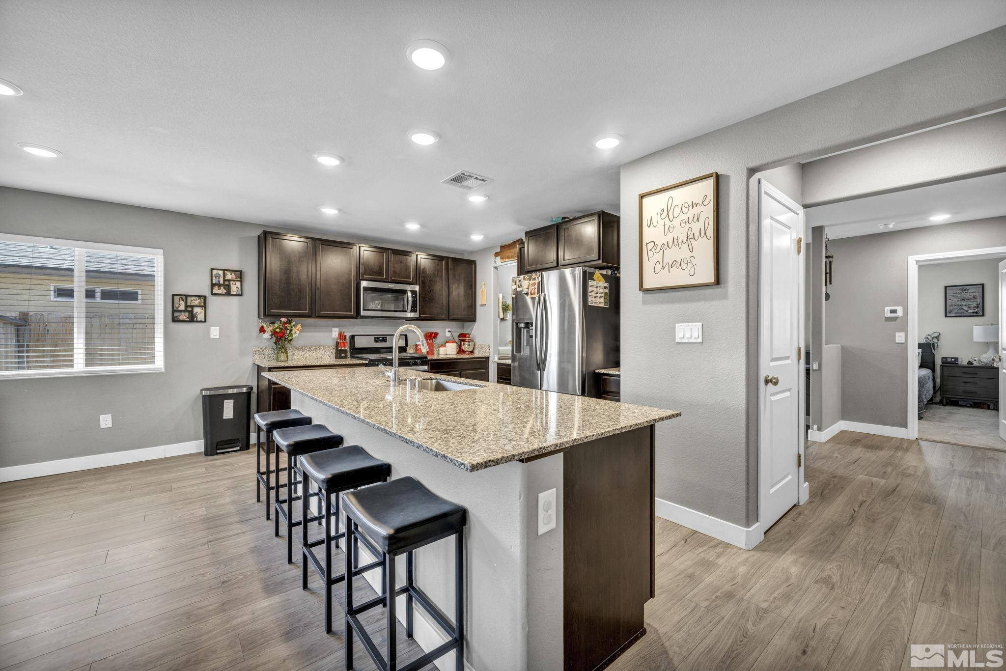 623 Yerington Drive Reno, NV 89506 - Photo 4 of 40 a kitchen with stainless steel appliances kitchen island granite countertop a refrigerator a stove and a sink with wooden floor
