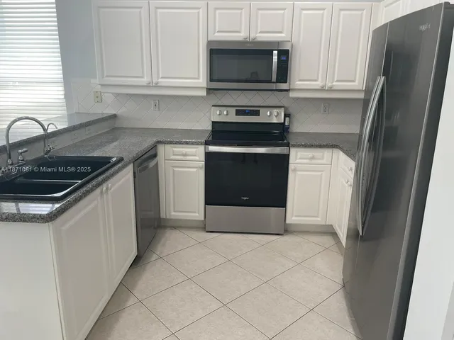 a kitchen with stainless steel appliances granite countertop a refrigerator stove and sink
