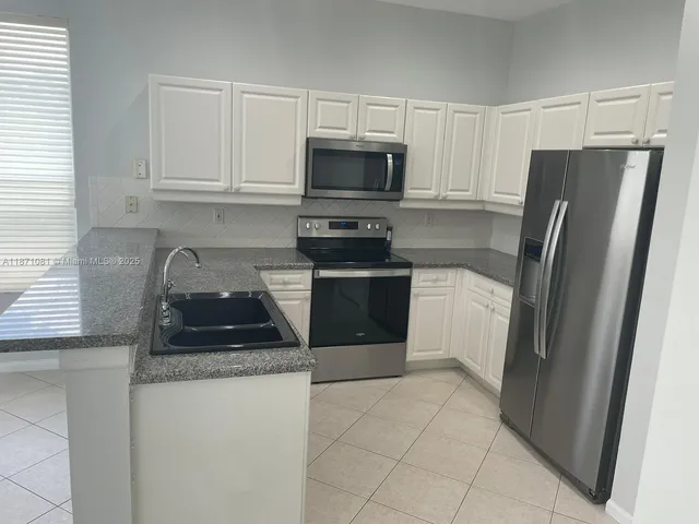 a kitchen with granite countertop a refrigerator and a stove