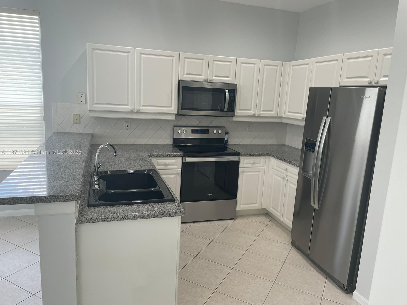 2145 Southwest 150th Avenue Miramar, FL 33027 - Photo 15 of 36 a kitchen with granite countertop a refrigerator and a stove