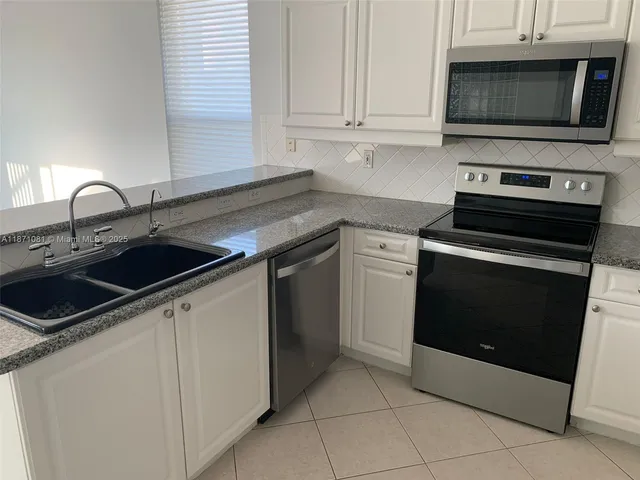 a kitchen with granite countertop white cabinets and stainless steel appliances