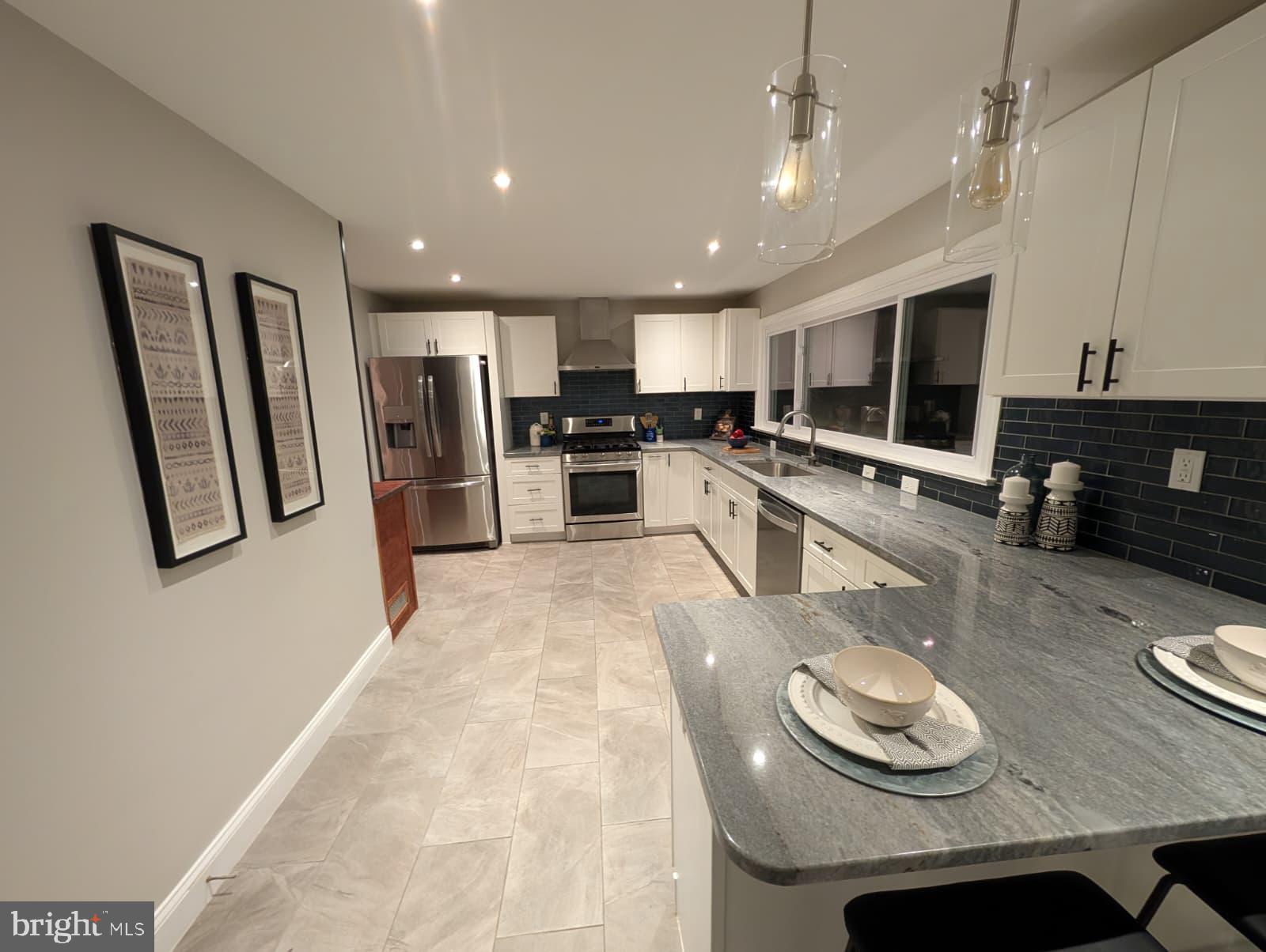 a kitchen with stainless steel appliances granite countertop a sink refrigerator and cabinets