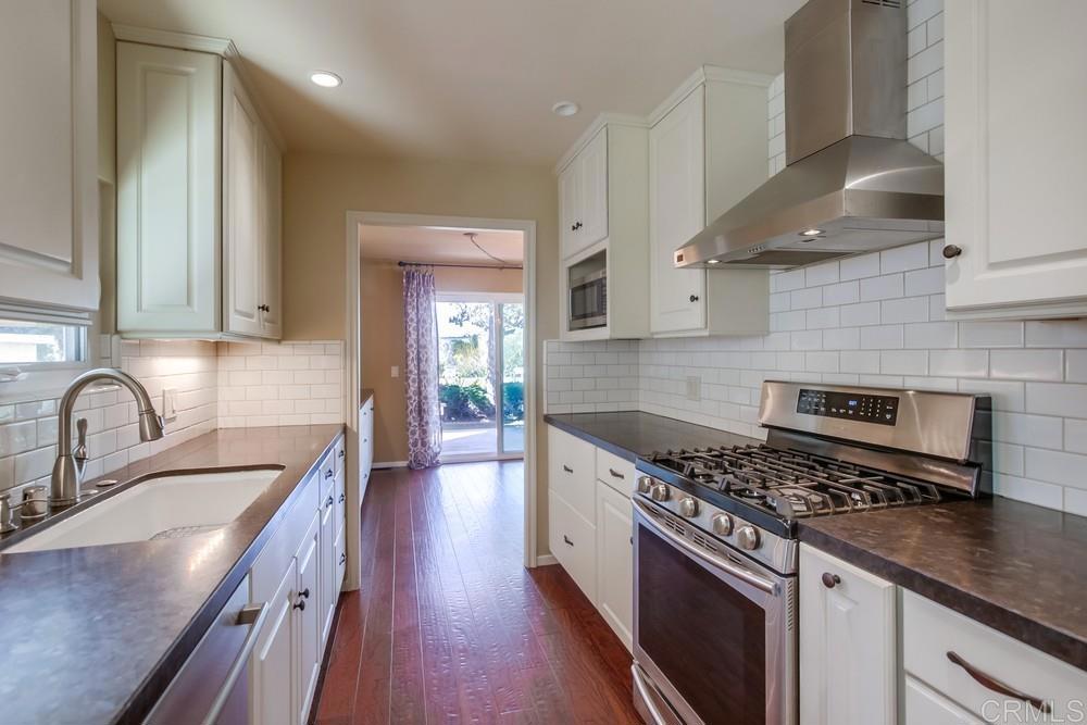 4993 Old Cliffs Road San Diego, CA 92120 - Photo 5 of 20 a kitchen with stainless steel appliances granite countertop a sink a stove and a wooden floors