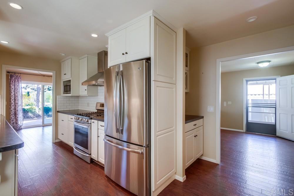 4993 Old Cliffs Road San Diego, CA 92120 - Photo 6 of 20 a kitchen with stainless steel appliances a refrigerator cabinets and wooden floor