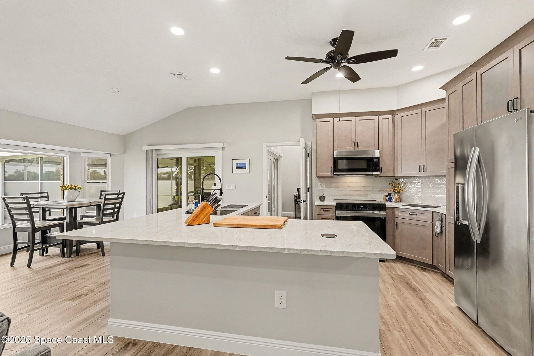 355 Lake View Lane Palm Bay, FL 32909 - Photo 10 of 49 a kitchen with stainless steel appliances kitchen island granite countertop a refrigerator a stove a sink a dining table and chairs with wooden floor