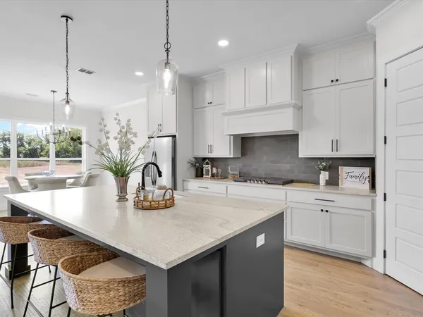 a kitchen with kitchen island granite countertop a table chairs in it and wooden floors