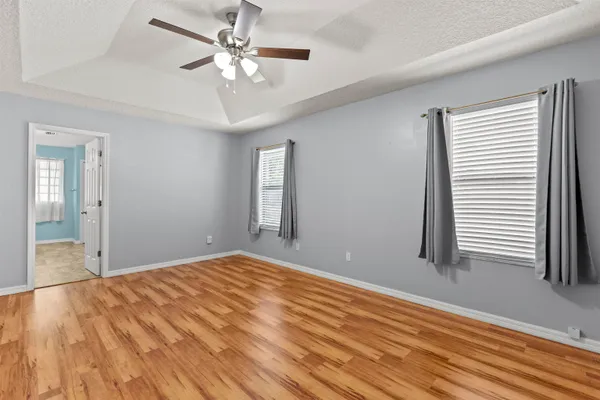 a view of an empty room with window and wooden floor