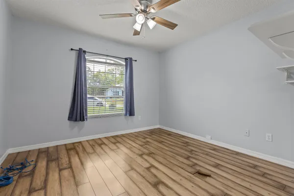 a view of an empty room with wooden floor and a window