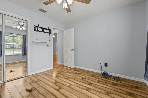 a view of empty room with wooden floor and fan