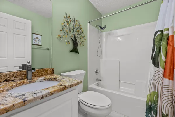 a bathroom with a granite countertop sink a toilet and a shower
