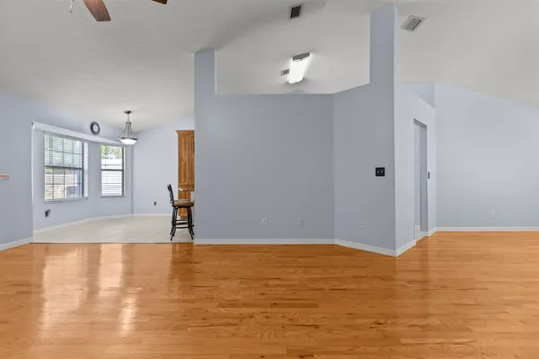 a view of an empty room with window and wooden floor
