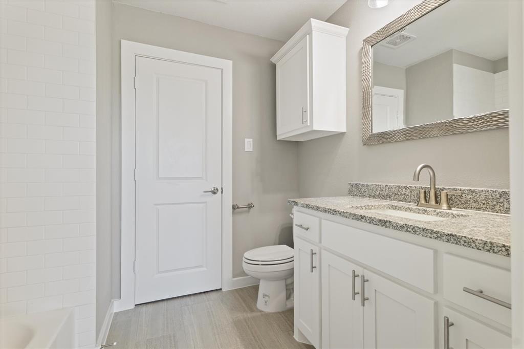 434 Cirrus Circle Muenster, TX 76252 - Photo 24 of 29 a bathroom with a granite countertop sink a toilet and a mirror