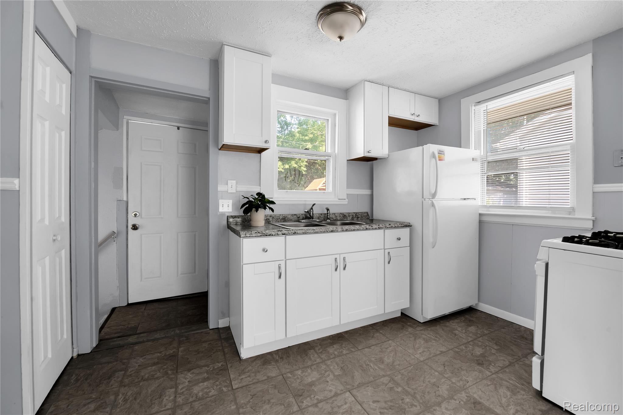 58925 Haven Ridge Road New Haven, MI 48048 - Photo 13 of 22 Kitchen with white cabinetry, white appliances, and a textured ceiling