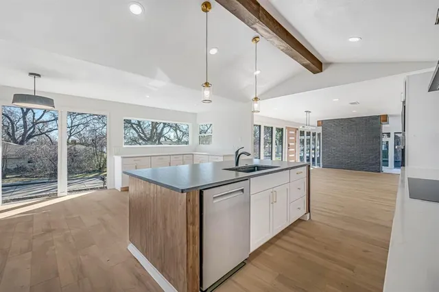 a kitchen with stainless steel appliances granite countertop a sink and wooden floor