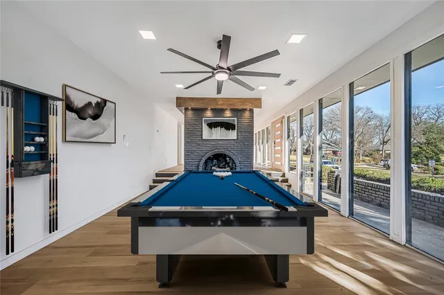 a room with wooden floor pool table and windows