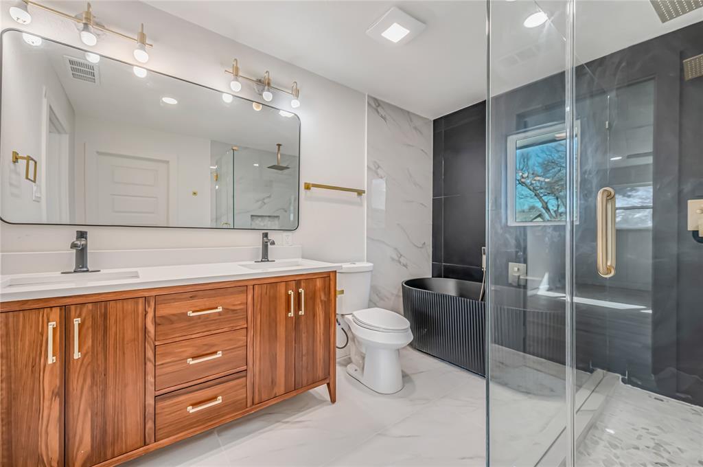 109 Pecan Drive Rowlett, TX 75087 - Photo 32 of 39 a spacious bathroom with a double vanity sink a toilet and a shower