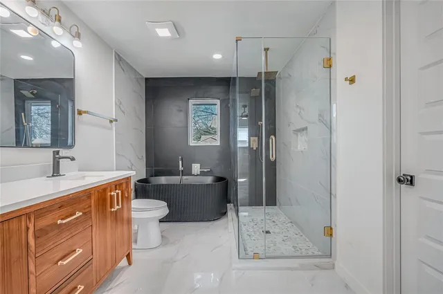 a bathroom with a sink a toilet a mirror and shower