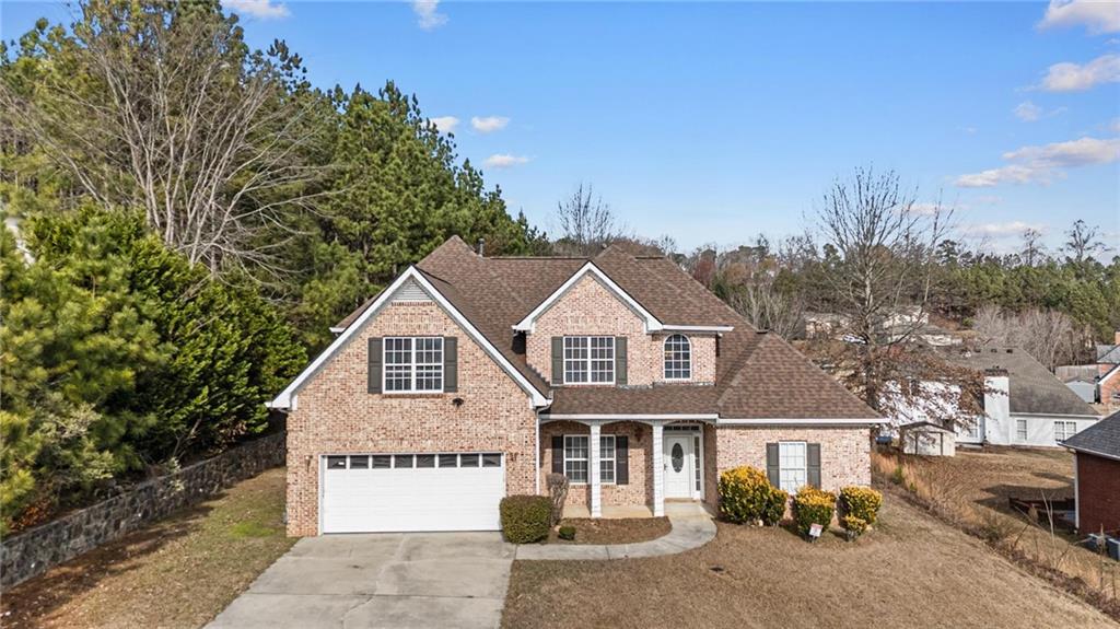 a view of a white house next to a yard with large trees