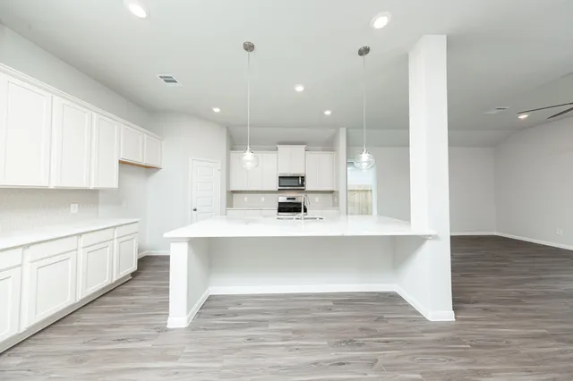 a large white kitchen with wooden floor