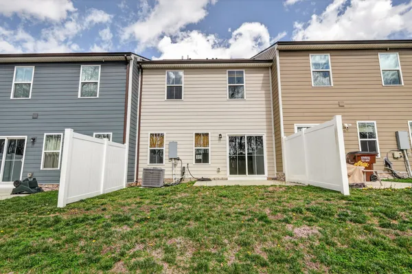a backyard of a white house with potted plants and a table and chairs