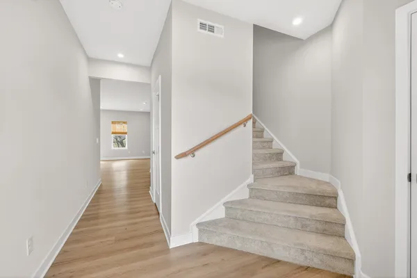 a view of staircase with wooden floor and white walls