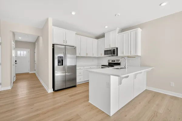 a kitchen with a refrigerator a stove top oven and wooden floor