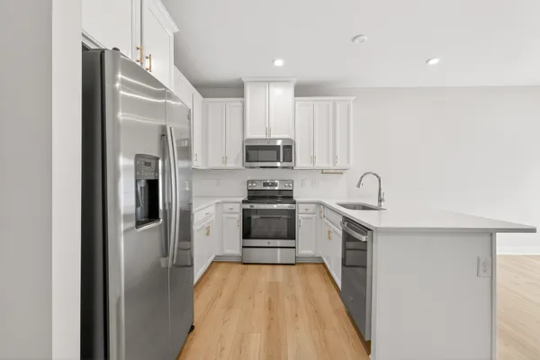 a kitchen with stainless steel appliances granite countertop a refrigerator a stove and a sink