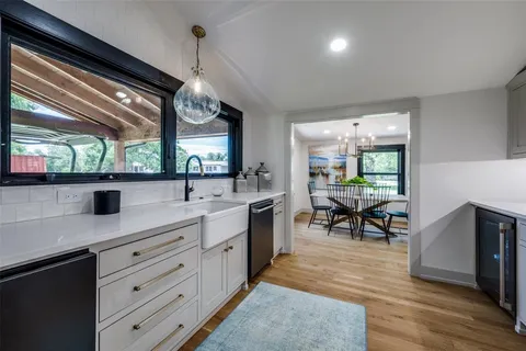 a kitchen with stainless steel appliances granite countertop sink dishwasher a dining table and chairs with wooden floor