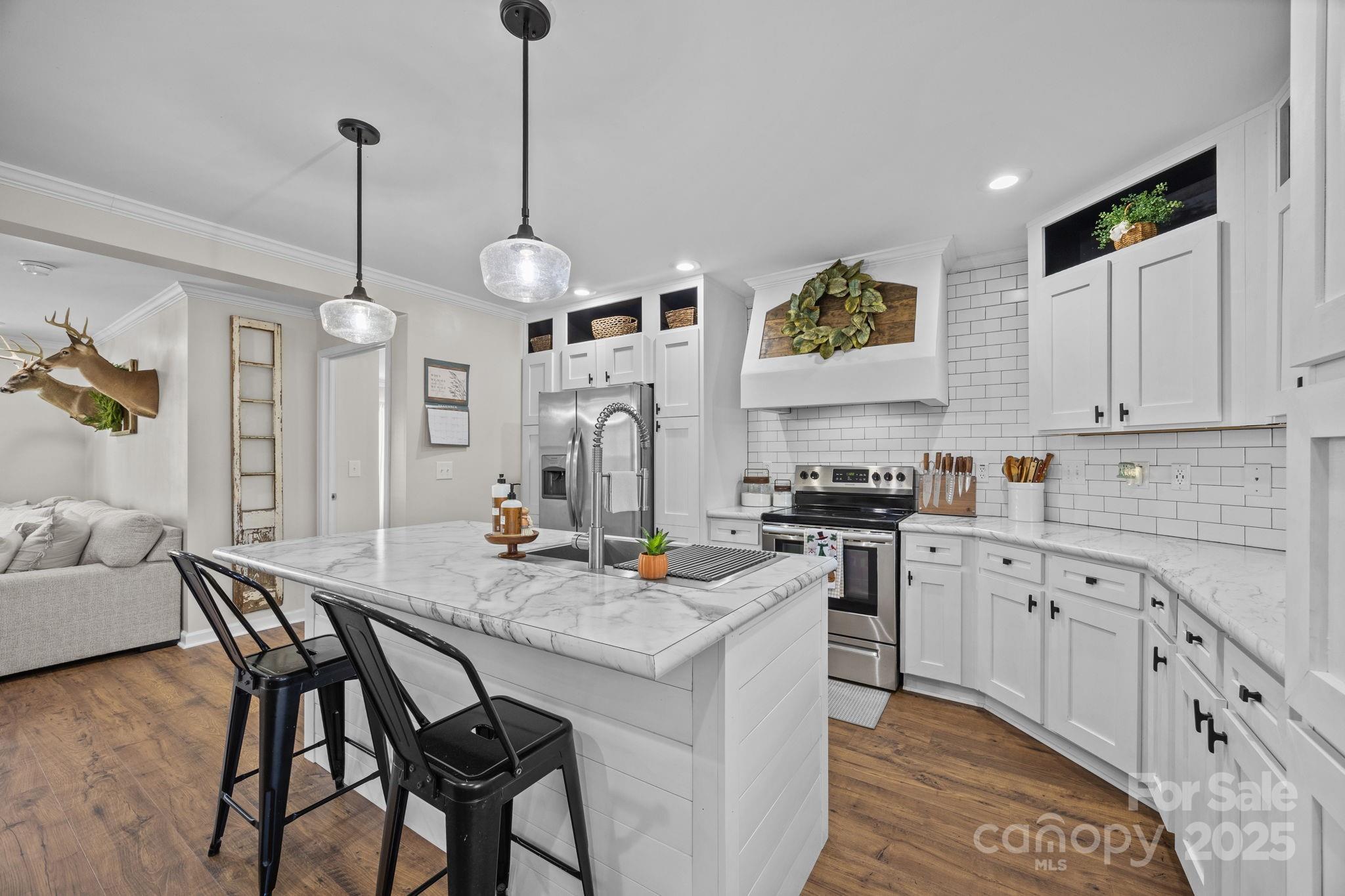 247 Aden Green Road Mill Spring, NC 28756 - Photo 15 of 48 a kitchen with stainless steel appliances granite countertop a stove a sink dishwasher a dining table and chairs with wooden floor
