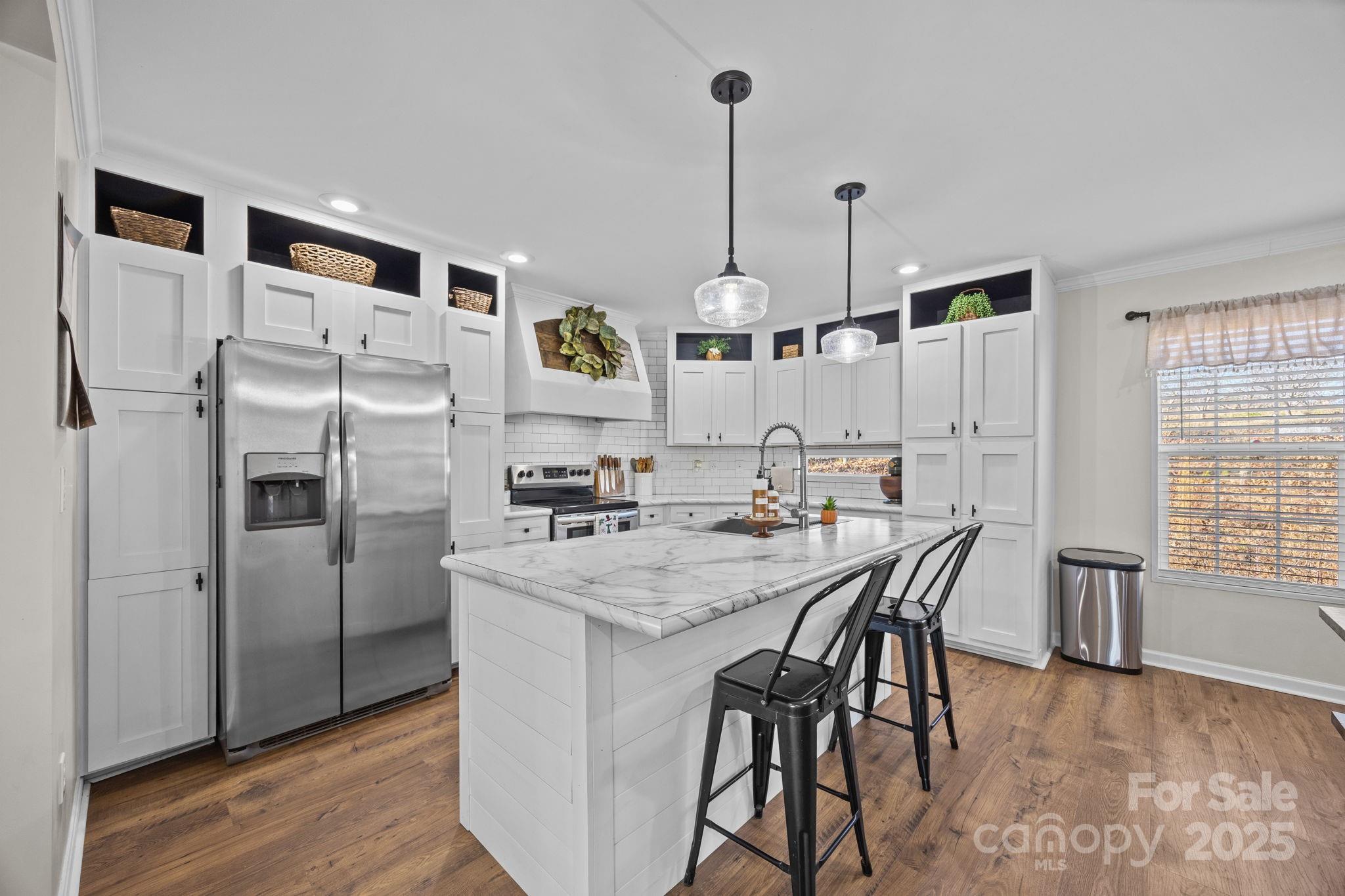247 Aden Green Road Mill Spring, NC 28756 - Photo 16 of 48 a kitchen with stainless steel appliances a refrigerator a stove a dining table and chairs with wooden floor