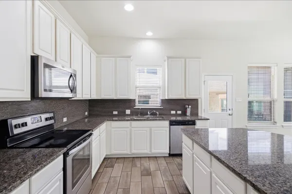 a kitchen with stainless steel appliances granite countertop a sink stove and cabinets