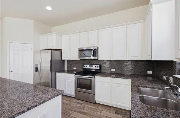 a kitchen with granite countertop a sink stove and refrigerator