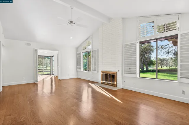 a view of empty room with wooden floor and floor to ceiling window