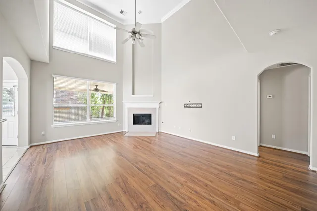 an empty room with wooden floor fireplace and windows