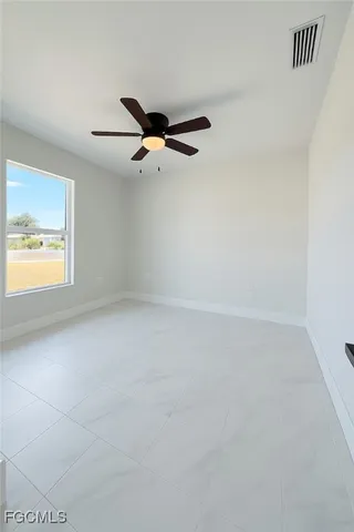 an empty room with windows and fan