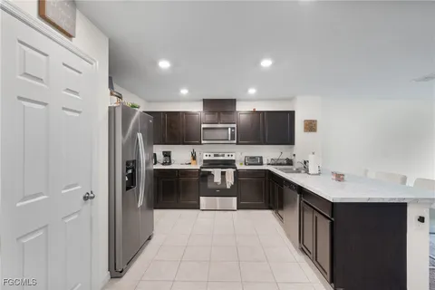 a large kitchen with stainless steel appliances kitchen island granite countertop a refrigerator and a sink