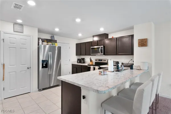 a large kitchen with stainless steel appliances kitchen island granite countertop a refrigerator and a sink