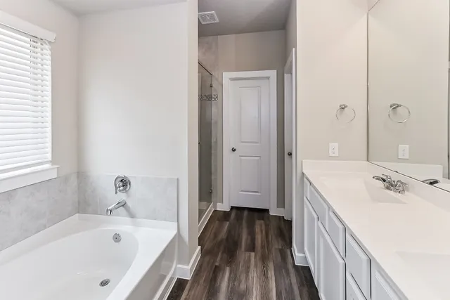 a bathroom with a tub a sink and a large mirror