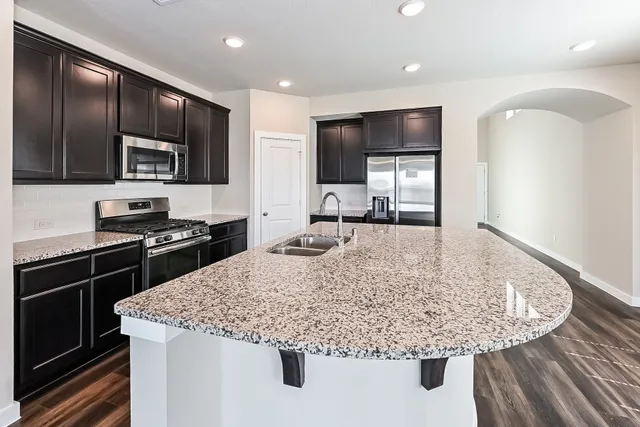 a kitchen with kitchen island granite countertop stainless steel appliances and sink