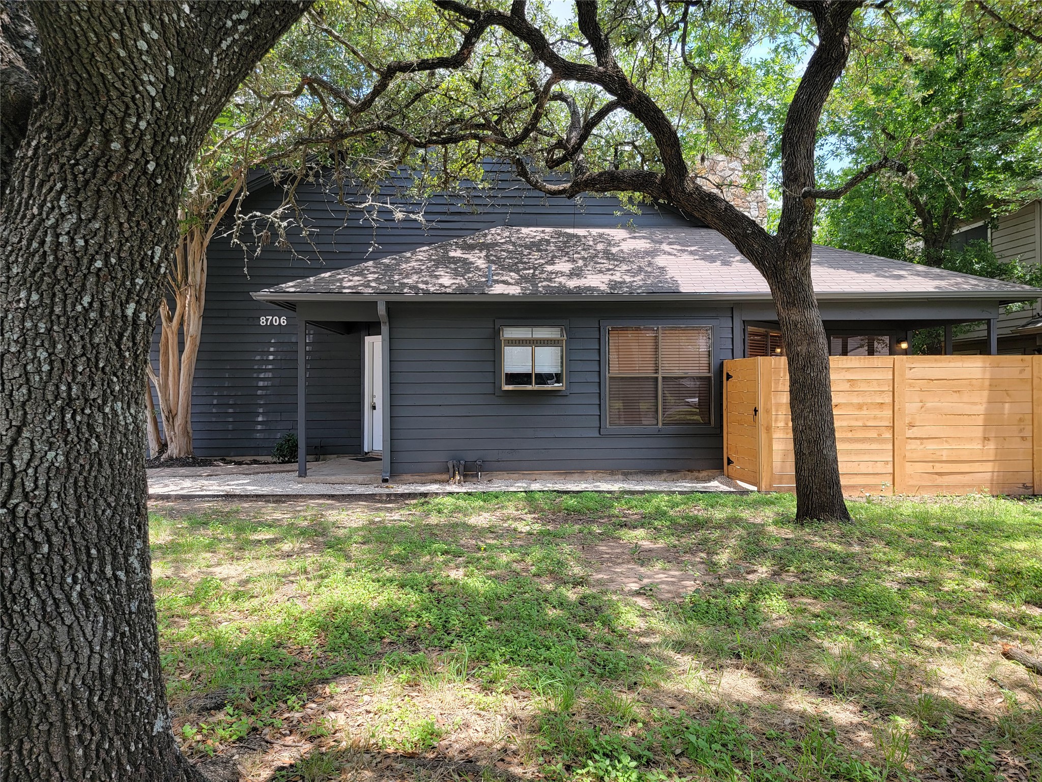 8706 Schick Road, Unit A Austin, TX 78729 - Photo 4 of 33 Mature trees shade this inviting residence, featuring a welcoming covered entrance and privacy fencing.