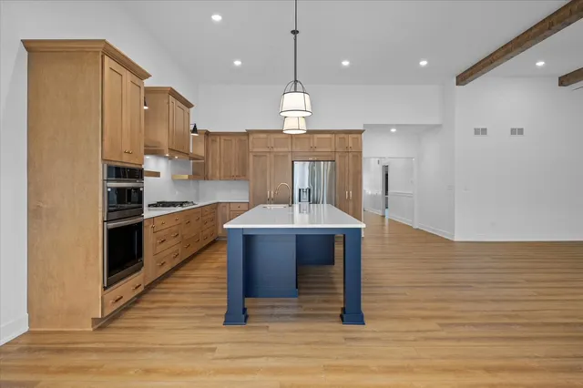 a kitchen with kitchen island stainless steel appliances a dining table chairs sink and cabinets
