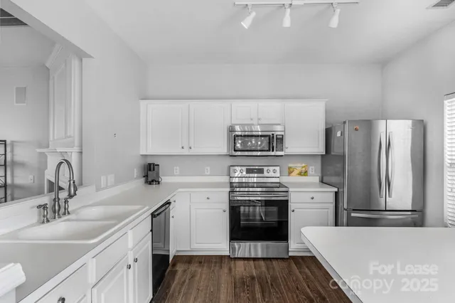 a kitchen with stainless steel appliances a sink cabinets and wooden floor