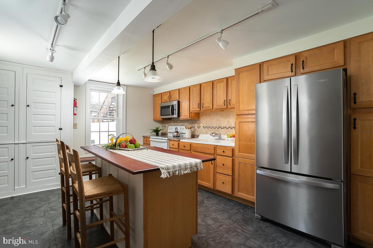 a kitchen with stainless steel appliances a refrigerator a stove a sink a dining table and chairs