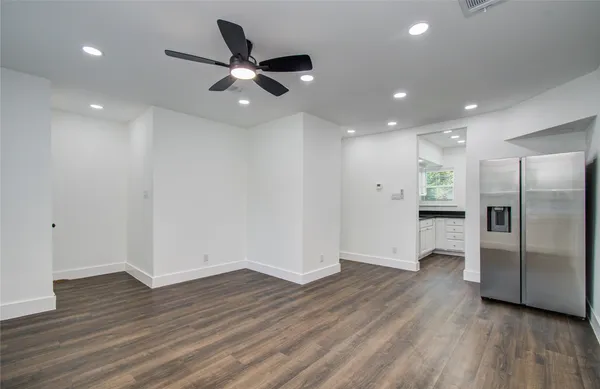 a view of an empty room with wooden floor a ceiling fan and windows