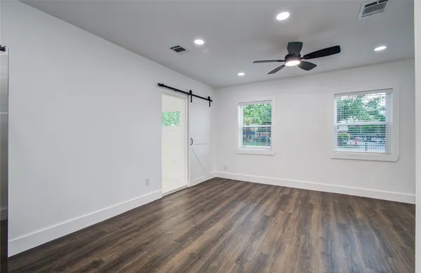 an empty room with wooden floor a ceiling fan and windows