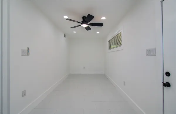 an empty room with ceiling fan and window