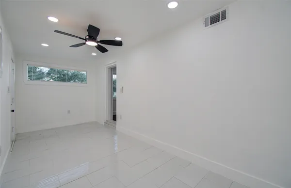 an empty room with wooden floor fan and windows