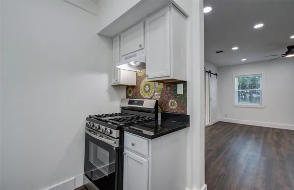 a kitchen with granite countertop a stove and a wooden floors